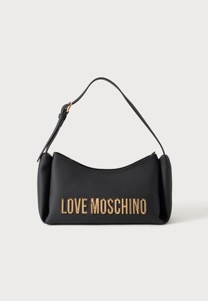 Sac Moschino noir avec lettrage doré et courte bandoulière sur fond blanc.