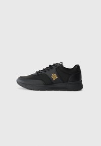 Black sneakers made of synthetic material with a smooth texture, featuring a gold logo detail, round toe, and lace-up design.