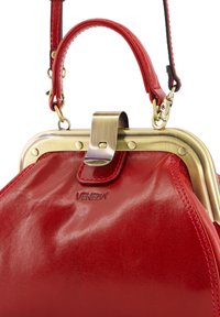 Red leather handbag with a glossy finish, featuring a brass frame, clasp closure, and a short leather strap. Notable logo embossed on side.