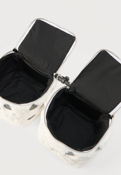 Δύο μικρές λευκές τσάντες από συνθετική γούνα με μαύρη εσωτερική επένδυση, ανοιχτές πλατιά με ασημένια φερμουάρ και κούμπωμα ορατά σε απλό φόντο.