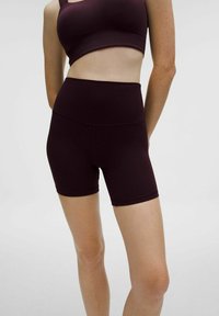 Pantalones cortos deportivos en color burdeos con una cintura alta, hechos de un tejido suave y elástico. Presentan un diseño ajustado y una longitud corta.