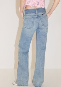Jeans a zampa d'elefante azzurro chiaro con vita alta, design a cinque tasche, cuciture visibili e vestibilità rilassata, mostrati da dietro.
