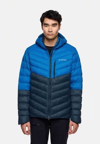 Giacca imbottita blu e blu scuro con cappuccio, dotata di chiusura lampo e motivi trapuntati diagonali. Leggera, adatta per attività all'aperto.