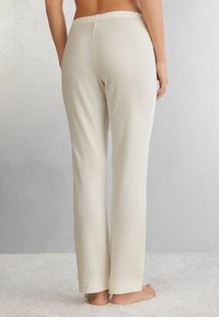 Wafelbrei loungebroek in lichtbeige, met een relaxte pasvorm, elastische tailleband en omgeslagen zomen. Materiaal heeft een gestructureerde afwerking.
