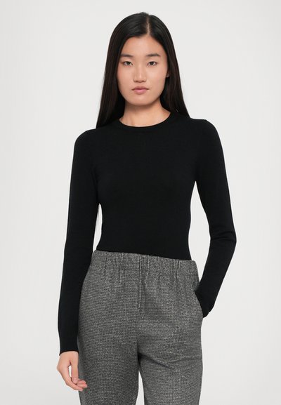 Black long-sleeve top made of a soft material, featuring a round neckline. Paired with loose-fitting gray patterned pants.