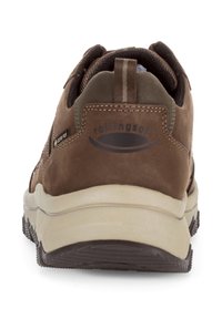 Sneaker en suède marron et cuir avec une semelle en caoutchouc beige, présentant un logo à l'arrière et une boucle pour un enfilage facile. Surface texturée.