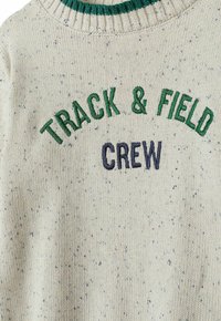 Pulover tricotat de culoare gri deschis, cu un text brodat "TRACK & FIELD CREW" în verde și bleumarin. Prezintă un guler cu nervuri, cu accente verzi și o textură strălucitoare.