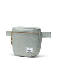 Borsa Herschel realizzata in tessuto verde chiaro testurizzato, con zip dorata, manico laterale e etichetta bianca del marchio sul davanti.