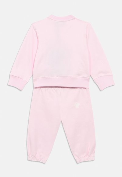 Σετ ροζ φούτερ και παντελονιού φόρμας από απαλό ύφασμα. Διαθέτει ελαστικά μανίκια, στρογγυλή λαιμόκοψη και μικρό λογότυπο στο παντελόνι.