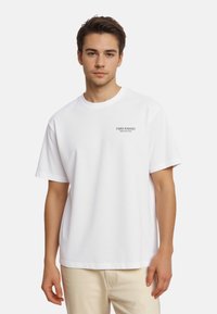 T-shirt en coton blanc à manches courtes, col rond, avec le texte noir "Papis Bakery" sur la poitrine gauche. Design simple et classique.