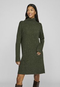 Abito a maglia con collo alto in verde oliva scuro, caratterizzato da maniche lunghe e polsini e orlo a costine. Texture morbida con una vestibilità comoda.