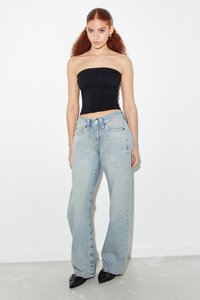 Top negru fără bretele, cu un design texturat, asortat cu blugi evazați bleu deschis, cu accente de studs metalice și o croială relaxată. Pantofi negri.