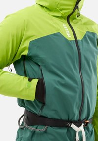 Veste imperméable verte et citron avec une fermeture éclair à l'avant, une capuche réglable, des poignets élastiques, et une ceinture avec une boucle pour sécuriser l'équipement.