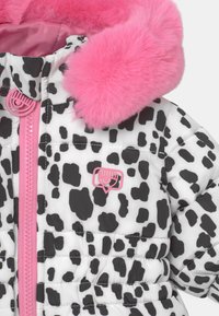 Bílá péřová bunda s černými skvrnami, s růžovou umělou kožešinou na kapuci, růžovým zipem a malým růžovým logem na hrudi.