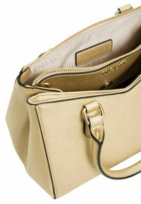 Borsa a mano oro con finitura metallica texture, chiusura con zip e accenti neri. L'interno include un'etichetta con il marchio e diversi scomparti.