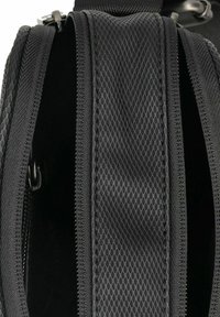 Borsa nera con materiale testurizzato, design a rete e doppie aperture con zip, che mette in mostra uno spazio interno con un rivestimento scuro.