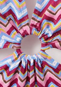 Elastic de păr din material textil cu margini strânse, în dungi zigzag de culoare roz, albastru, galben, maro și alb pe un fundal deschis.