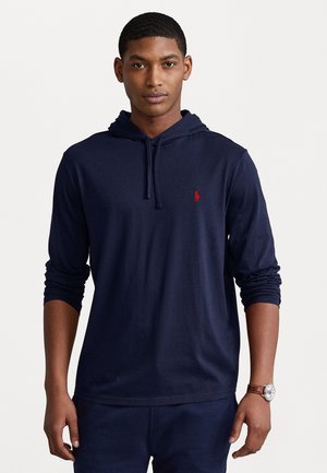 Tamnoplava hoodie od mekanog materijala s dugim rukavima. Sadrži prednji kengur džep i mali crveni logo na prsima.