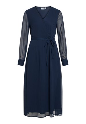 Tumši zils apmetuma kleita ar dziļu V veida kakla izgriezumu, garām caurspīdīgām piedurknēm un saišu jostu. Iespējamā plūstoša svārku daļa ar slāņainu tekstūru.