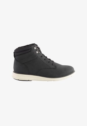 Czarne skórzane botki na kostkę z białą podeszwą środkową, teksturowanym kołnierzem, sześcioma metalowymi oczkami i czarnymi sznurowadłami. Gładka powierzchnia z kontrastowymi szwami.