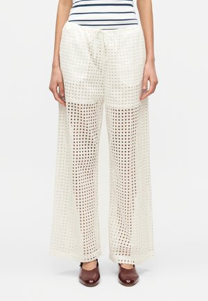 Lette, kremfargede palassobukser med rutemønster, utstyrt med snor i livet og vide ben. Matt tekstur, avslappet design.