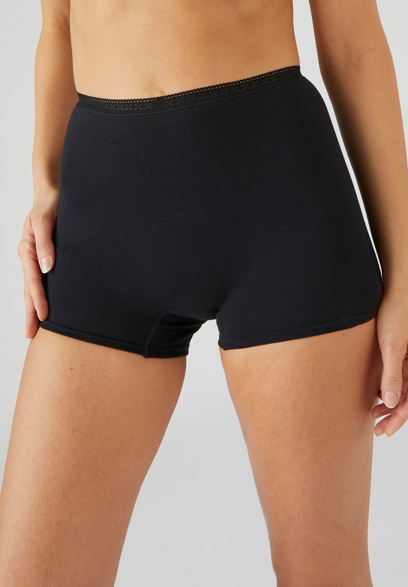 Shorts negros de talle alto hechos de un material suave, con un borde de encaje en la cinturilla y un diseño ajustado que llega hasta la mitad del muslo.
