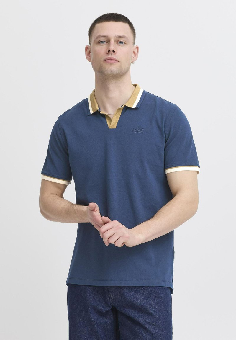 Mornarsko polo majica s kontrastnim rumenim ovratnikom in belimi robovi. Mehka bombažna tkanina, kratki rokavi in subtilno blagovno znamko na prsih.