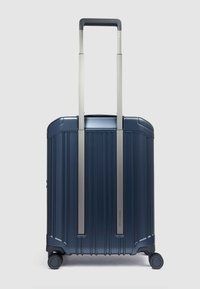 Marineblauer Hartschalenkoffer mit gerippter Oberfläche, ausziehbarem Metallgriff, vier Rollen für Mobilität und einer strukturierten Oberfläche für Haltbarkeit.