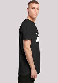 Black t-shirt featuring a crew neck, short sleeves, and a graphic print design on the front. Made from a soft, textured fabric.