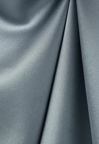 Lehká, hladká saténová látka v tlumené šedé barvě, vykazující jemný lesk a texturu s mírnými záhyby a splýváním.