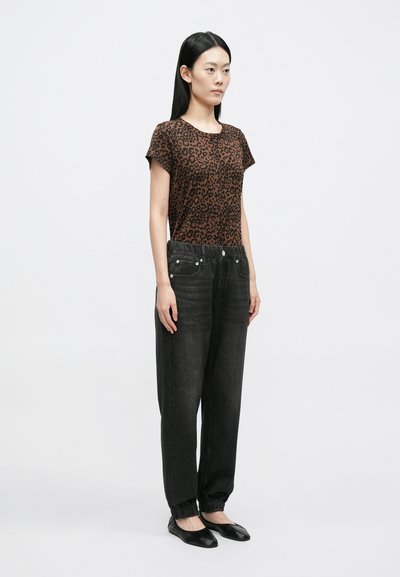 Brązowy, krótki top w cętki lamparta, zestawiony z wysokim stanem, luźnymi, ciemnoszarymi dżinsami z elastycznymi ściągaczami u dołu i widocznymi guzikami.