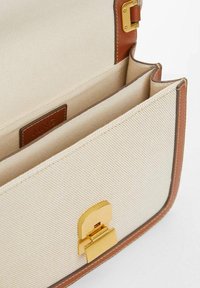 Rectangular beige canvas handbag with brown leather trim, gold-tone clasp, and multiple interior compartments.