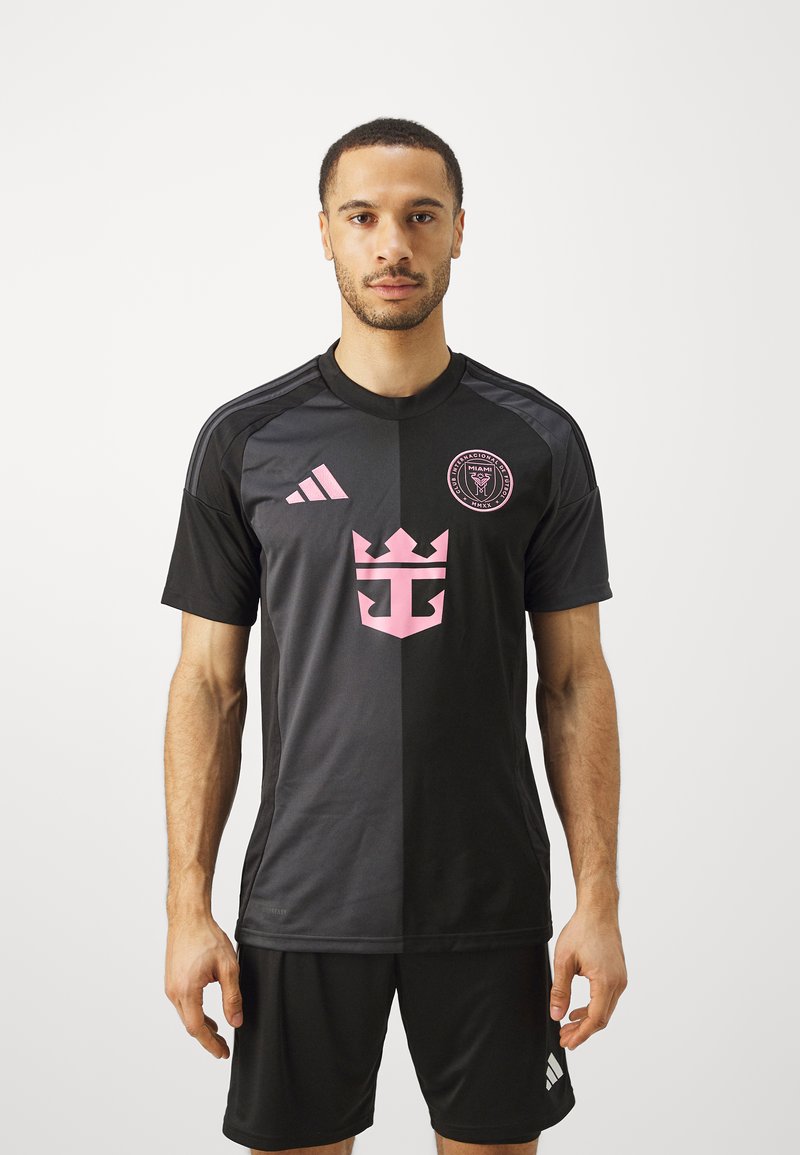 Crna nogometna majica s ružičastim akcentima, logotipom s krunom i Adidas trakama. Dizajn je u bojama blokiran s okruglim izrezom i kratkim rukavima.