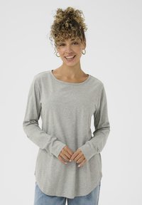 Lys grå langærmet skjorte med rund halsudskæring, blød tekstur og sidelæg. Parret med lyseblå denim jeans.