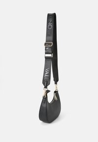 Svart skinn skulderveske med en buet form, gullfarget hardware og en avtagbar rem med teksten "VALENTINO" i hvitt.
