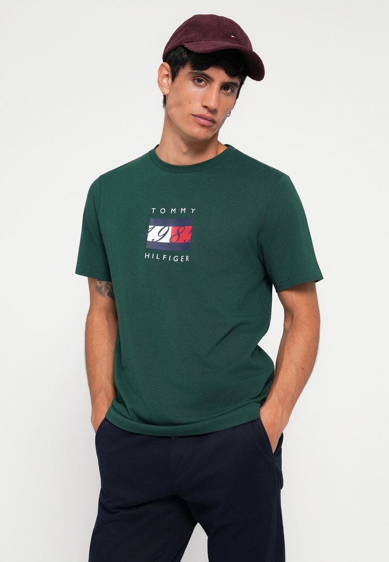 Camiseta de algodón verde con estampado de logo en rojo, blanco y azul; cuello redondo, manga corta y corte relajado.