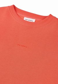 Koraļļu mikroflece, kas izgatavota no mīksta auduma, ar apaļu kakla izgriezumu un ribotām piedurknēm. Tuvumā apakšmalai ir diskrete izšūta logo "OH APRIL".