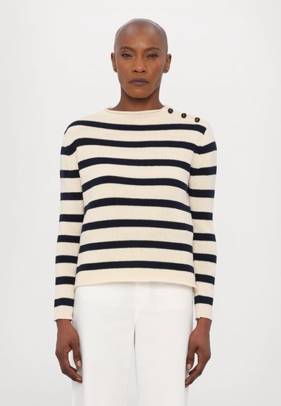 Pull rayé crème avec des lignes horizontales navy, présentant un col rond et trois boutons noirs sur l'épaule gauche ; texture côtelée.