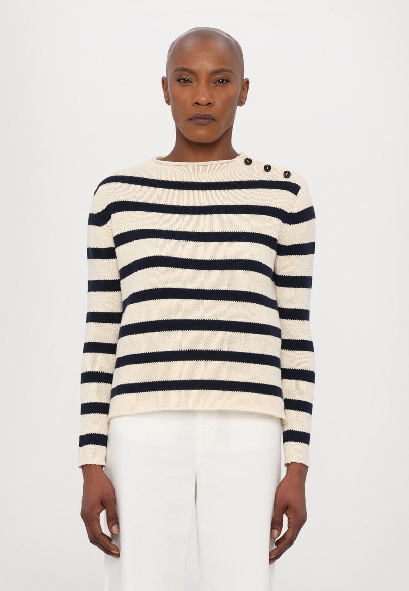 Maglione a righe crema con strisce orizzontali blu navy, dotato di un collo rotondo e tre bottoni neri sulla spalla sinistra; texture a coste.