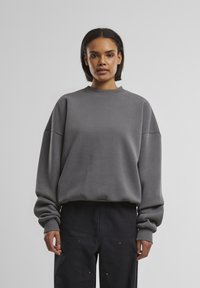 Grå sweatshirts med en afslappet pasform, ribbet rund hals og brede ærmer. Lavet af blødt stof, med en glat tekstur og enkelt design.