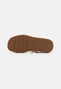 Brown rubber sole with a textured finish, featuring horizontal grooves for grip. Lightweight and flat design, marked with "Clarks."