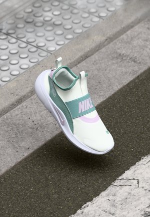 Zapatilla de Nike con un diseño en verde menta claro y blanco, estilo slip-on con una correa gruesa y un logotipo prominente, parte superior texturizada y una suela acolchada.