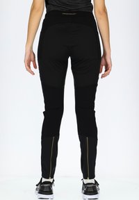Black athletic pants with a fitted design, featuring a high waistband, zippered ankle accents, and textured paneling on the legs.