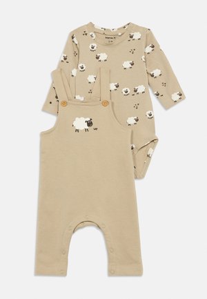 Beige baby romper with wooden buttons and matching long-sleeve bodysuit, both featuring white sheep patterns.
