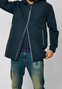 Tmavě modrá venkovní bunda s předním zipem, nastavitelnou kapucí a dvěma bočními kapsami, vyrobená z lehkého, voděodolného materiálu.