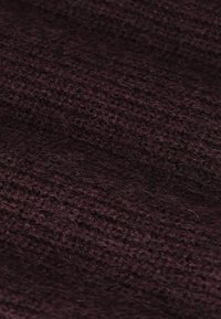 Donker bordeauxrood gebreide stof met een gestructureerd, fuzzy oppervlak, met een losse steekpatroon voor extra diepte en warmte.