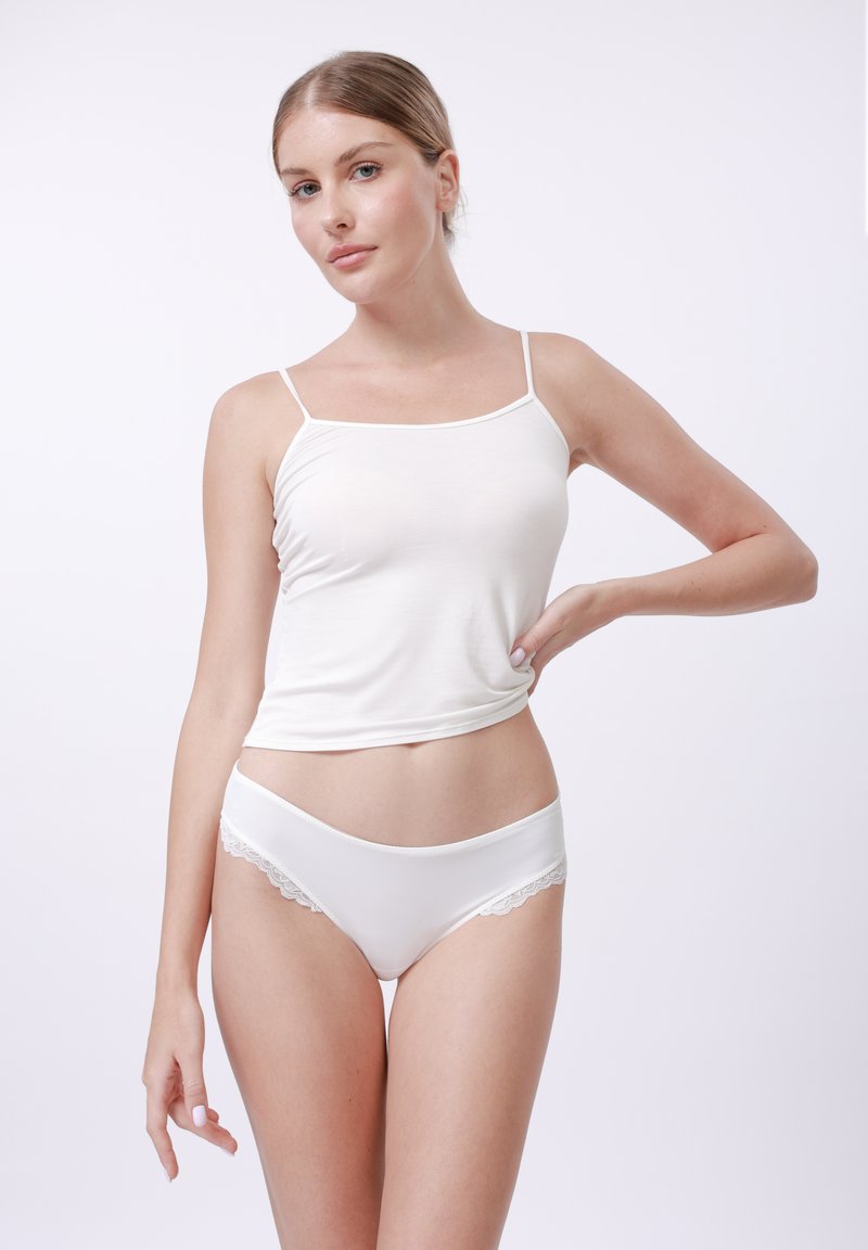 White camisole top with thin straps and a fitted design, paired with white panties featuring lace accents along the edges.