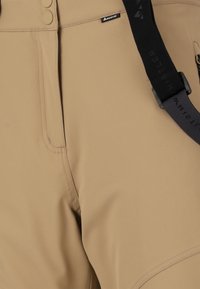 Tan, textuurstof broek met een aansluitend ontwerp, voorzien van twee knopen en een zwarte verstelbare band met logo-detail op de tailleband.