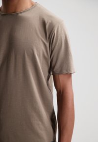 Korte mouw, crew-neck T-shirt in licht taupe, gemaakt van zachte stof met een gladde textuur, met een licht beschadigde zoom.