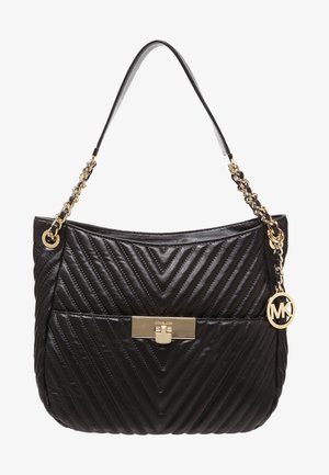 Bolso negro de cuero acolchado con asa de cadena dorada, cierre frontal dorado y charm circular con la marca colgando de la correa.